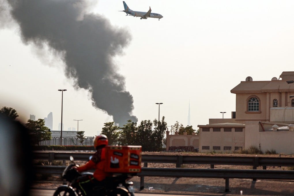 A FlyDubai aircraft prepares for landing as smoke rises from an ongoing fire near Dubai International Airport on Monday. Photo: TNS