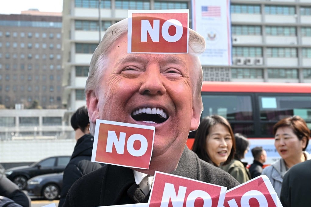 A protester wears a mask of US President Donald Trump in front of the US embassy in Seoul, South Korea, on March 16, during a demonstration against Trump’s request to dispatch warships to the Strait of Hormuz. Photo: AFP