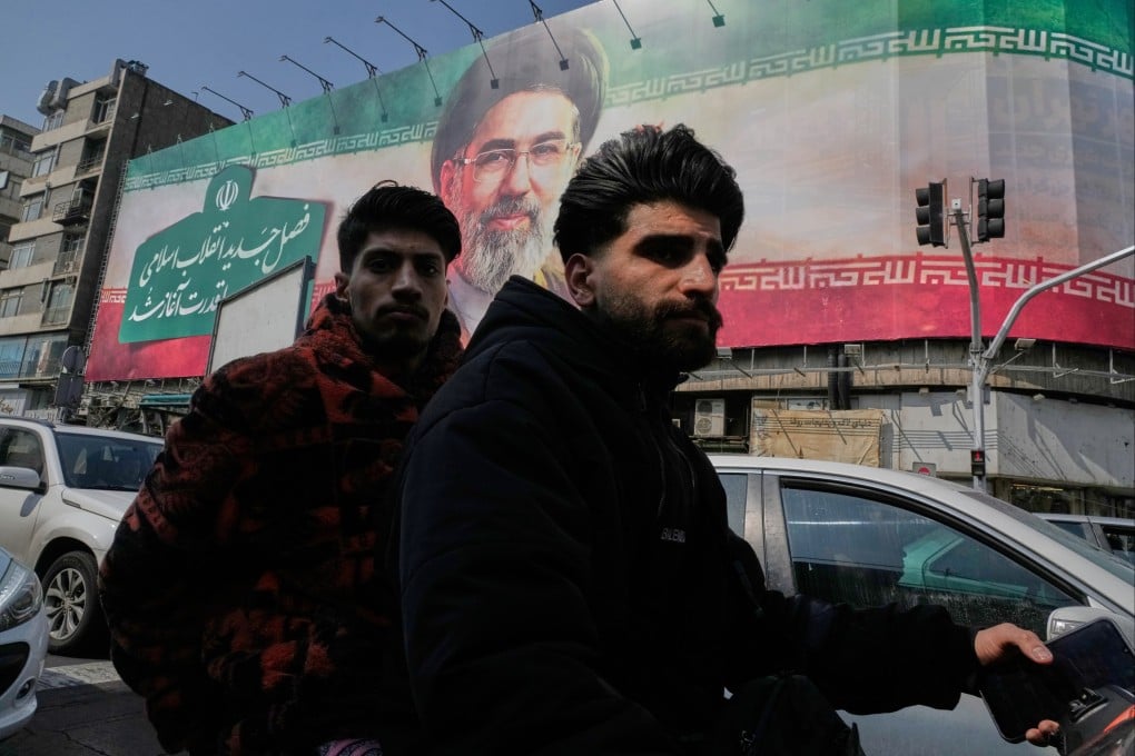 Two men ride their motorbike past a billboard of Iranian Supreme Leader Mojtaba Khamenei in Tehran. Photo: AP