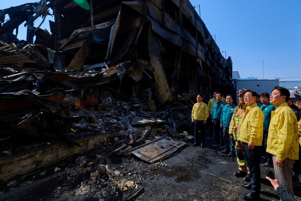 South Korean President Lee Jae Myung and other officials inspect what remains of a factory in Daejeon on Saturday, after a huge fire that killed 14 people. Photo: via Reuters