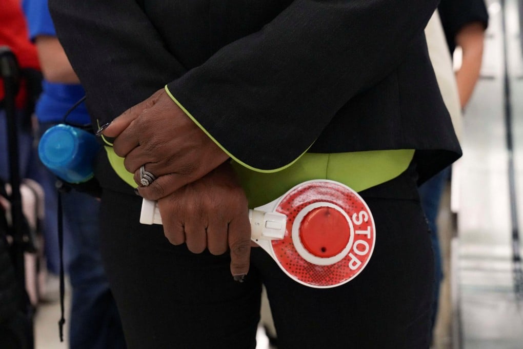 An airport employee holds a stop-and-go light-up sign while directing passengers waiting in long TSA queues at Hartsfield-Jackson Atlanta International Airport in Atlanta, Georgia, on Friday. Photo: Reuters