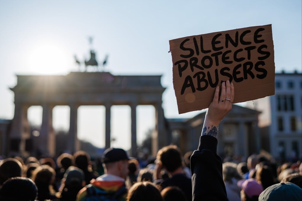 A protester holds a placard that reads “Silence protects abusers” during a rally at Brandenburg Gate in Berlin, Germany on Sunday. Photo: EPA