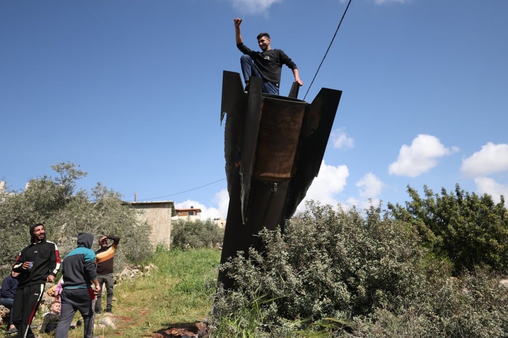 A Palestinian man climbs on the remains of a ballistic missile that landed in the West Bank village of Haris, near Salfit. Photo: EPA