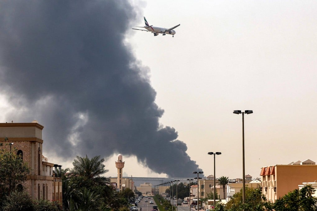 An aircraft prepares for landing as a smoke plume rises from a fire near Dubai International Airport on March 16. Photo: AFP
