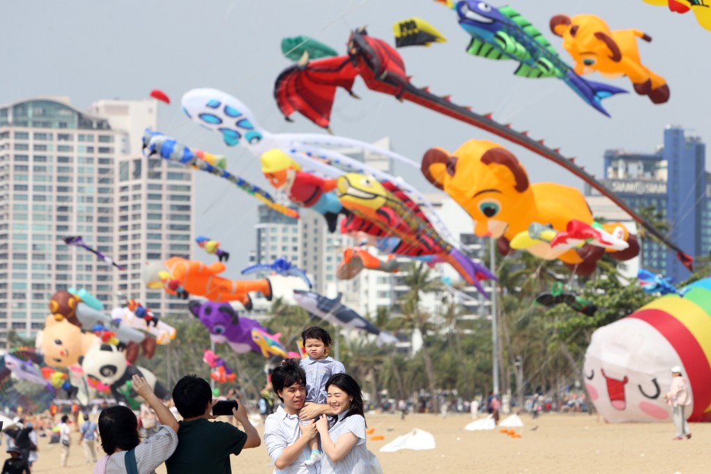 Tourists pose for photos with kites flying above a beach in Pattaya. Thailand is expecting up to 3 million fewer overseas tourists this year. Photo: Xinhua