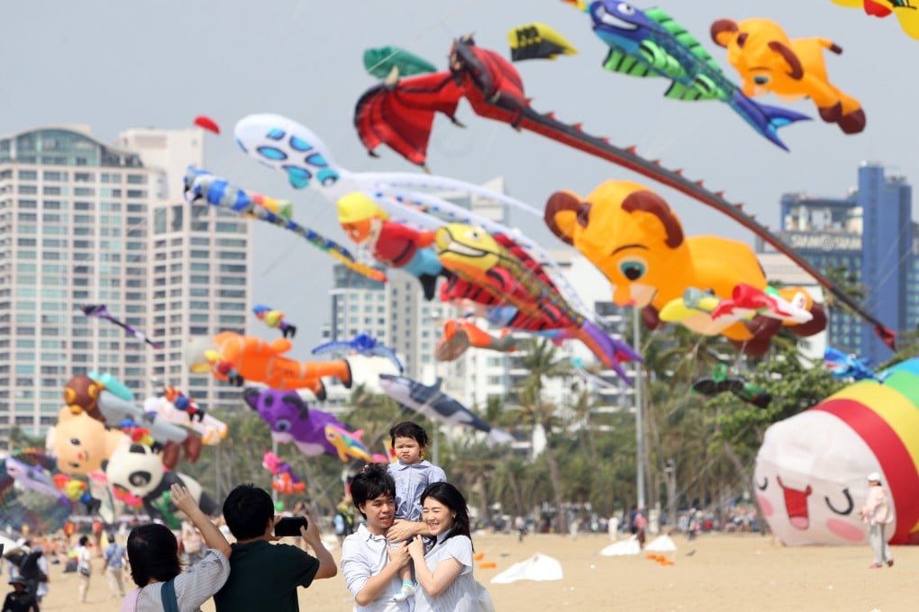 Tourists pose for photos with kites flying above a beach in Pattaya. Thailand is expecting up to 3 million fewer overseas tourists this year. Photo: Xinhua