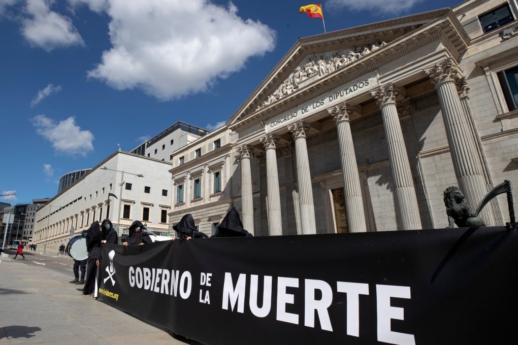 Anti euthanasia protesters stand outside the Spanish parliament in Madrid in March 2021. The banner reads “Government of Death” in Spanish. Photo: AP
