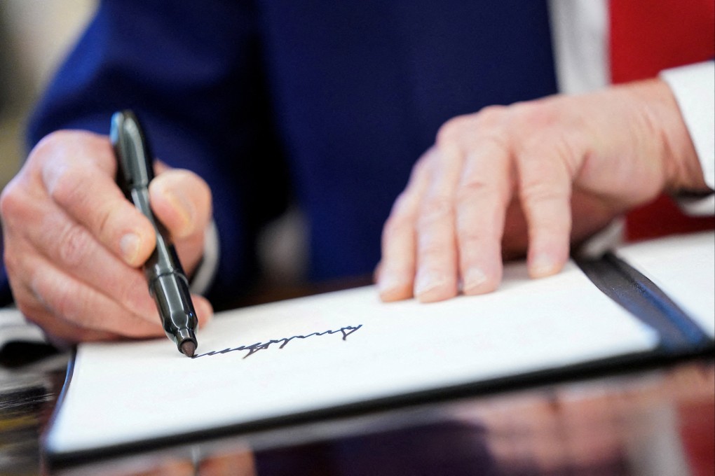 US President Donald Trump writes his signature. Photo: Reuters