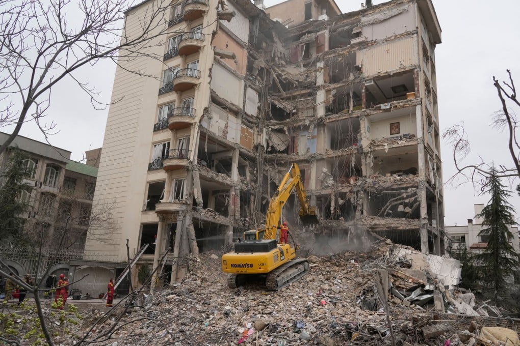 Iranian firefighters use an excavator to clear rubble from a residential building that was hit in an earlier US-Israeli strike in Tehran, on March 23. Photo: AP