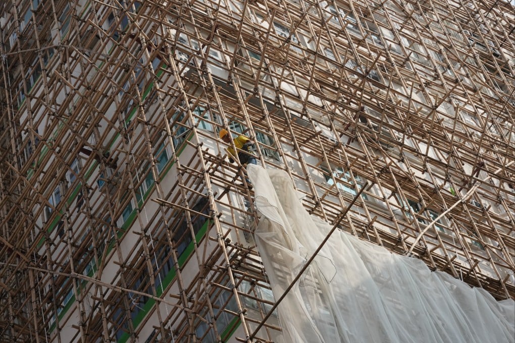 A worker removes scaffolding mesh on a building in Mong Kok. Photo: Jelly Tse
