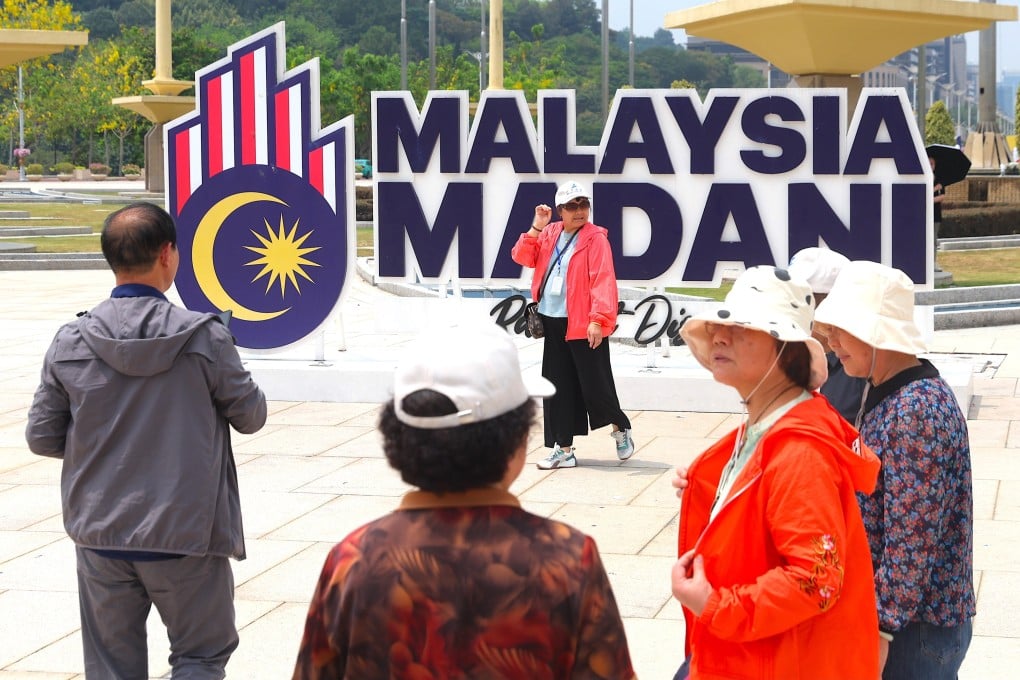 Tourists pose for photographs near the political slogan ‘Malaysia Madani’ (Civilised Malaysia) outside the Prime Minister’s Office in Putrajaya on Friday. Photo: EPA