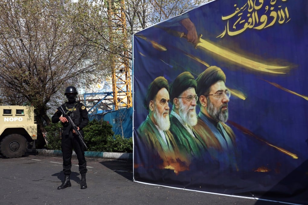 A member of the Iranian security forces stands guard next to a banner showing former and current Iranian supreme leaders in Tehran on Tuesday. Photo: EPA