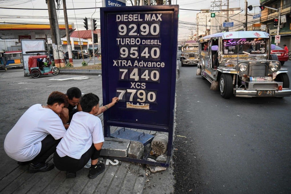 Workers change the price of fuel at a petrol station in Manila on March 17. Photo: AFP