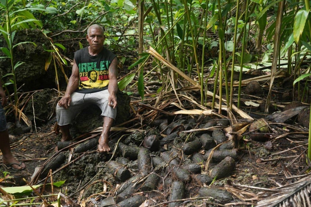 Billy, a resident of the village of Yandina in Russell Islands, Solomon Islands, sits next to unexploded munitions near his home. Photo: UNDP Pacific Office/Christopher Teasdale
