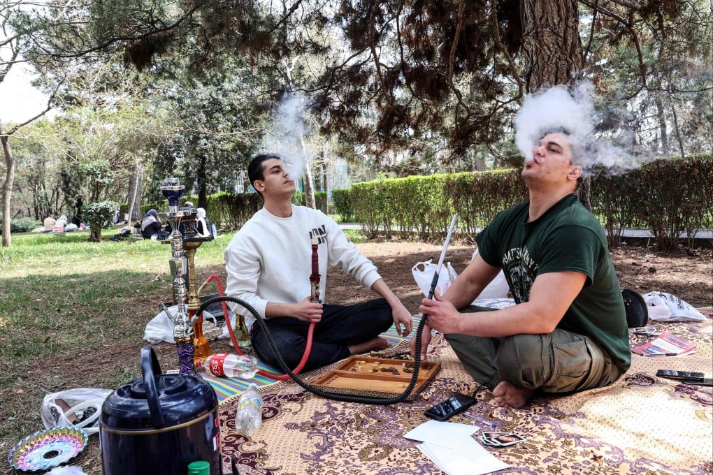 Iranian men smoke waterpipes as they sit in Tehran’s Mellat Park on Thursday. Photo: AFP