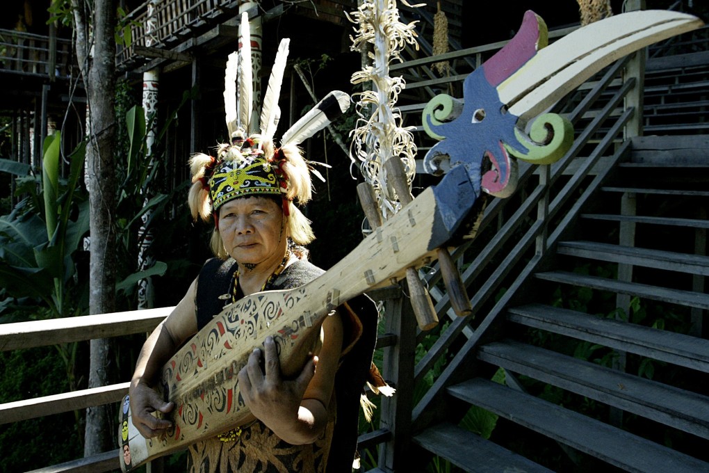 An indigenous musician plays a “sape” in front a traditional longhouse in Sarawak. Photo: Reuters