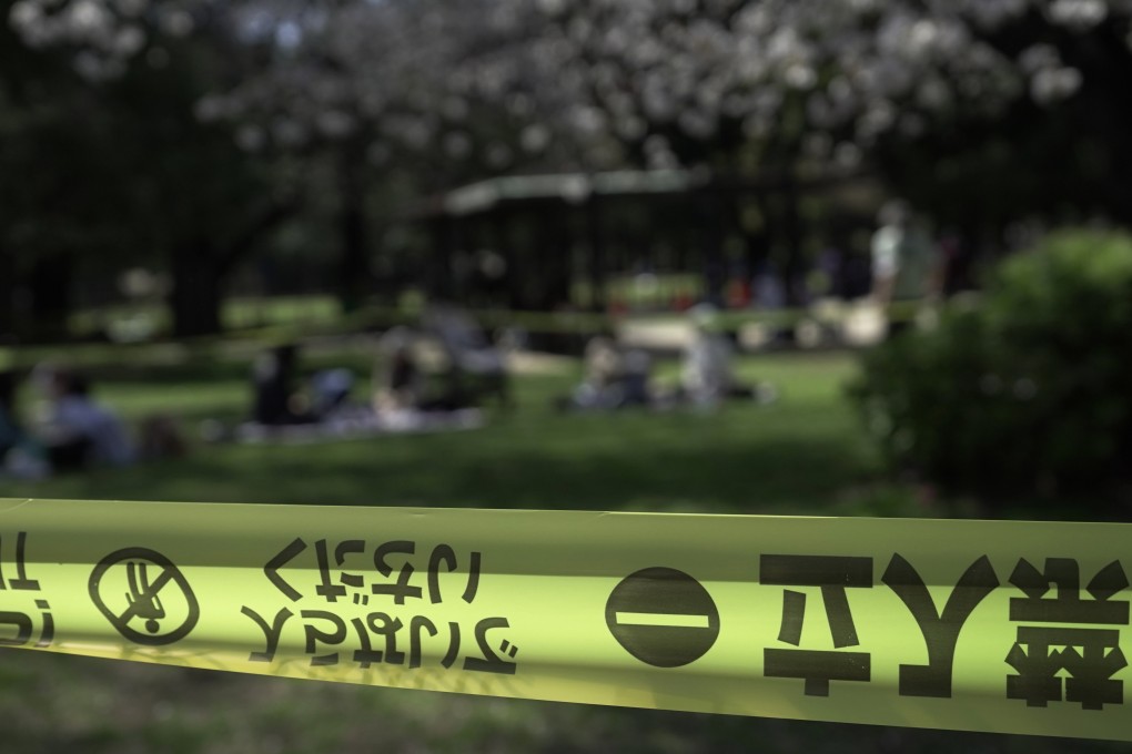People picnic outside a cordoned-off area set up to inspect the health of cherry blossom trees at Kinuta Park in Tokyo on Friday. Photo: AP