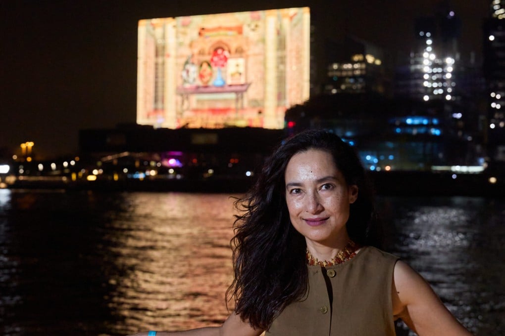 Shahzia Sikander stands in front of her work “3 to 12 Nautical Miles” (2026) playing on the giant TV screen on the M+ museum facade. The video will be shown every night until June 21. Photo: Winnie Yeung/Visual Voices