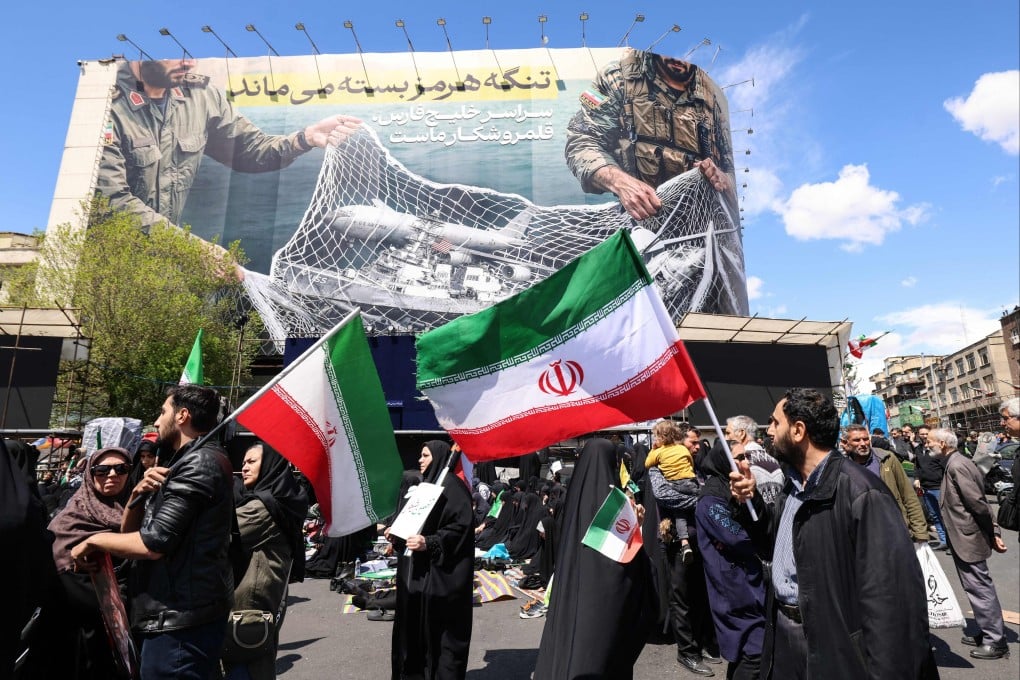 Iranians wave national flags beneath a large billboard in Tehran’s Revolution Square on Wednesday, following the announcement that the United States and Iran have agreed to a two-week ceasefire. Photo: AFP