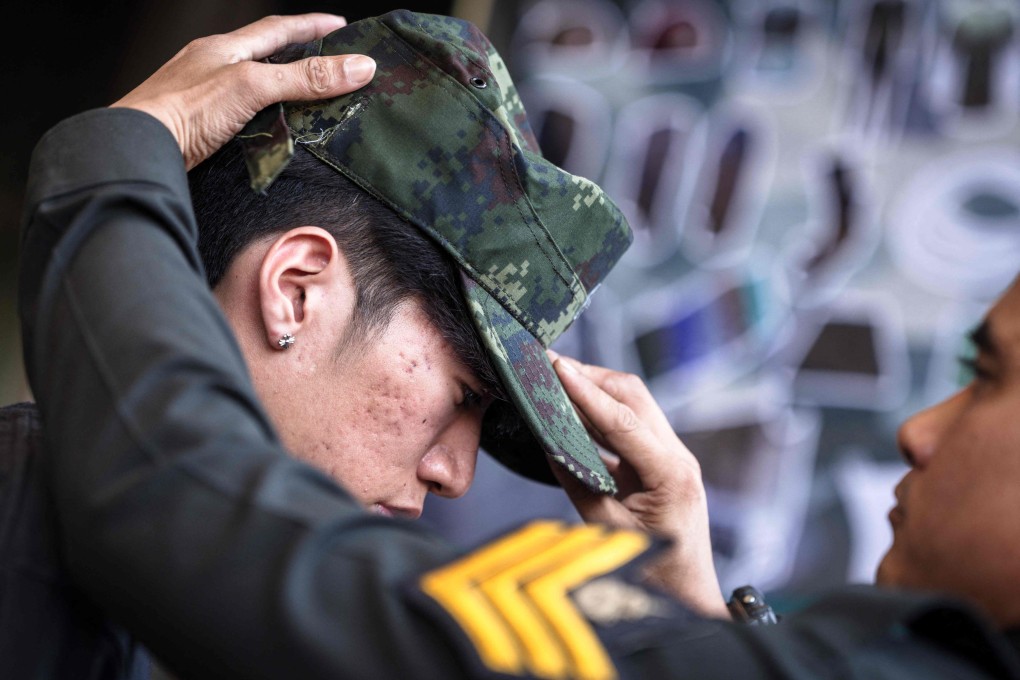 A soldier puts a hat on an enlisted man during the Thai military conscription drawing in Bangkok on Tuesday. Photo: AFP