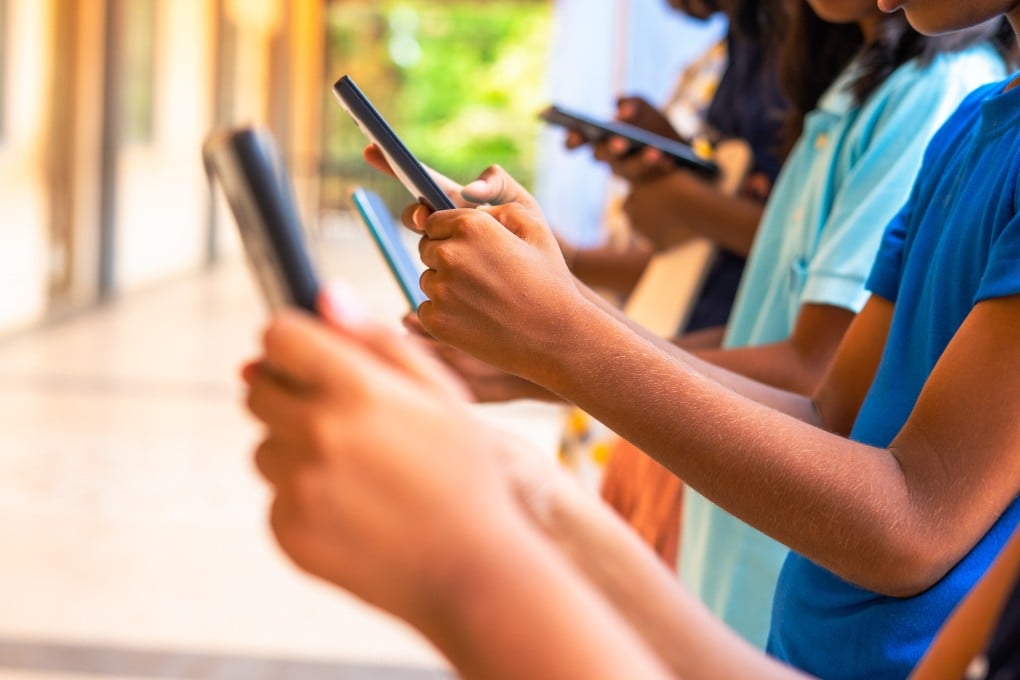 A group of children with mobile phones, all glued to their screens. Photo: Getty Images