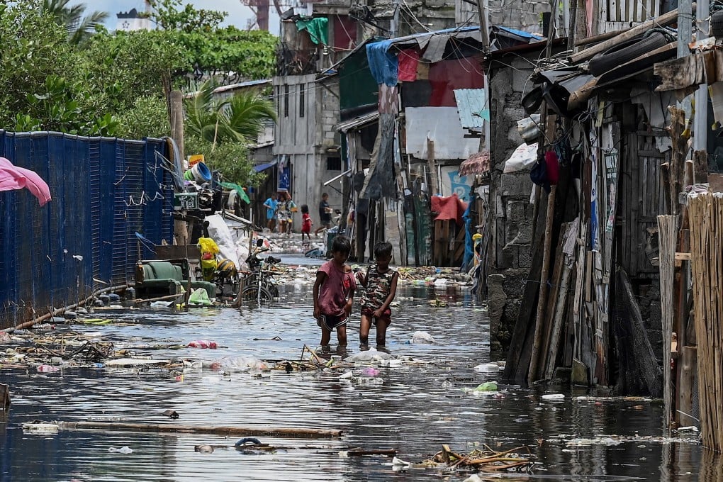 Children walk through a flooded area in Baseco, one of the biggest slums in Manila, the Philippines. Photo: AFP