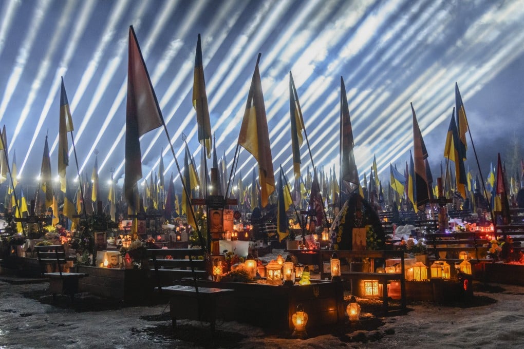 Beams of light illuminate the sky over the graves of fallen Ukrainian soldiers as friends and relatives take part in a joint prayer and candlelight vigil at Lychakiv Military Cemetery in Lviv, western Ukraine, on February 23. Photo: EPA