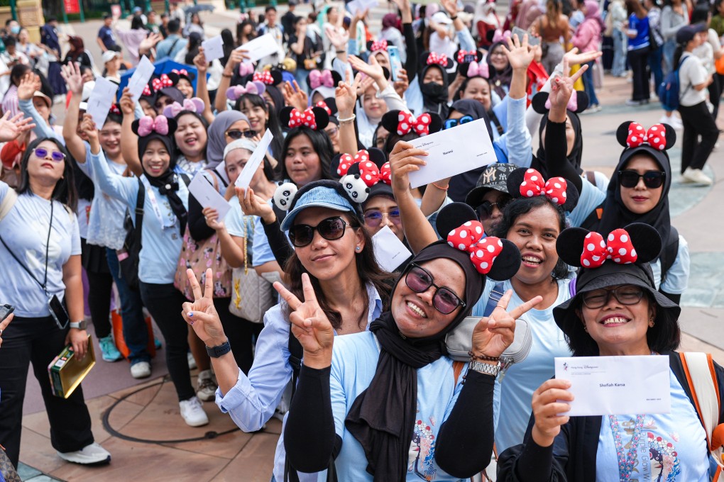 Domestic helpers pose for a photo with their free tickets to Hong Kong Disneyland. Photo: Eugene Lee