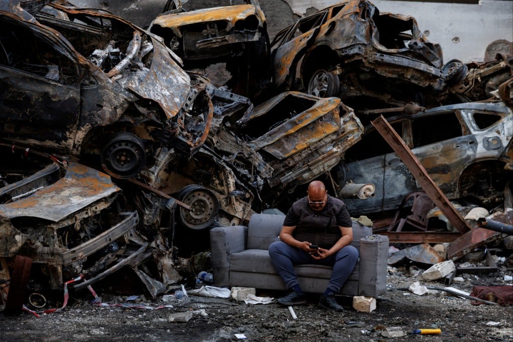 A man who said he survived an Israeli strike sits among piled damaged cars in Beirut. Photo: Reuter
