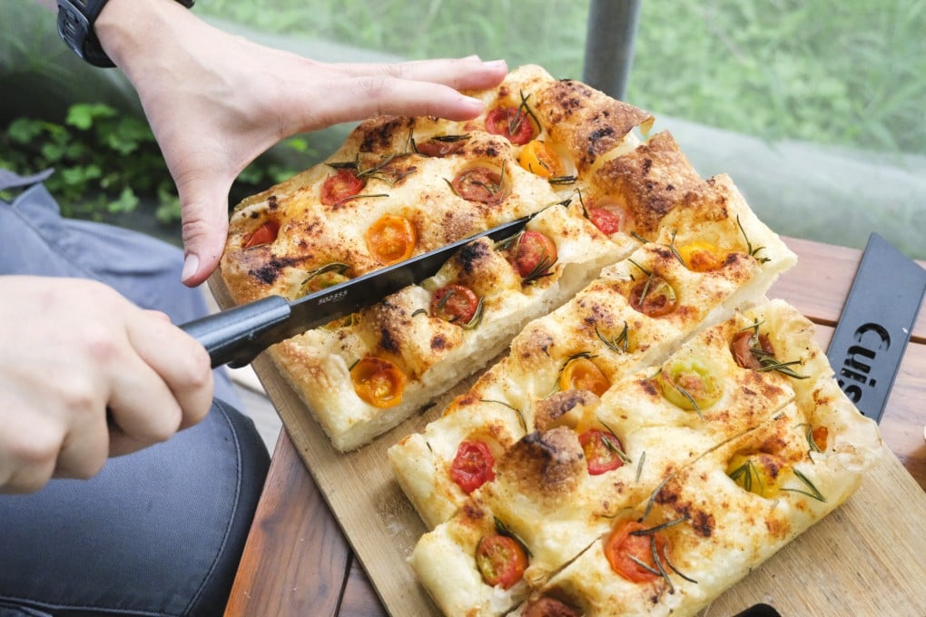 A fresh loaf of cherry tomato and rosemary focaccia baked by  Formless Daily, an artisanal small-batch bakery that uses ingredients from Hong Kong farms, is cut at a farm-to-table experience at Blue Girl Organic Farm in Tai Tong. Photo: Hei Kiu Au