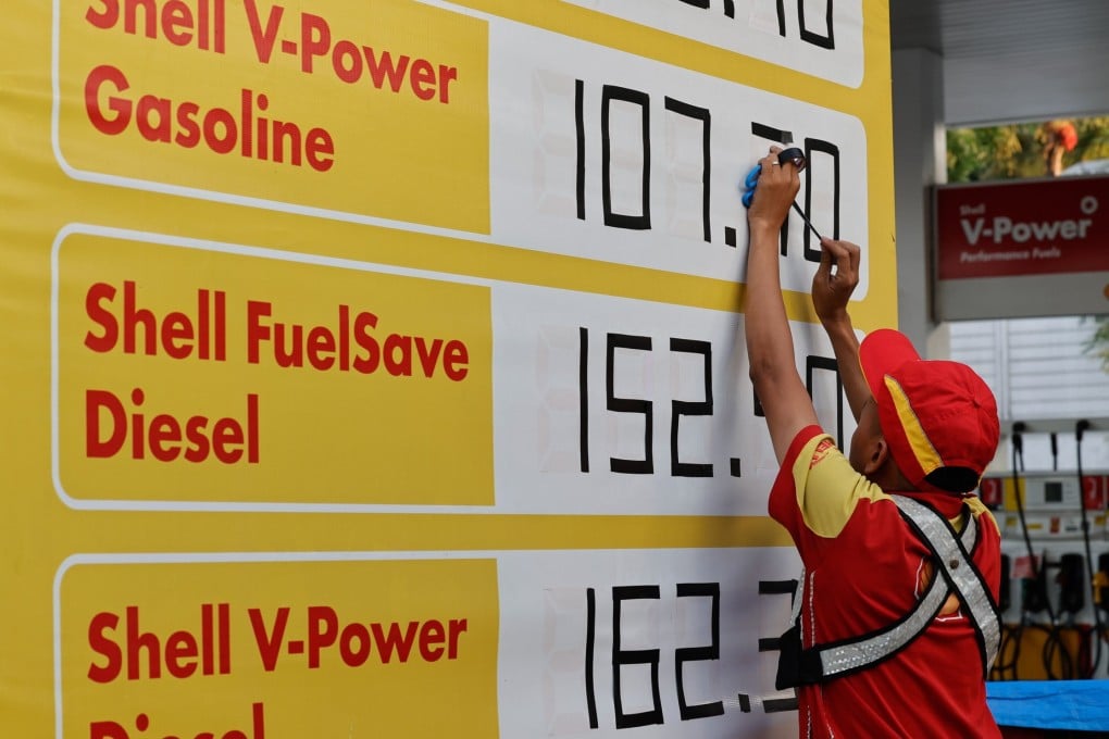 A pump attendant uses adhesive tape to change figures of fuel prices in Quezon City on April 7. Photo: EPA