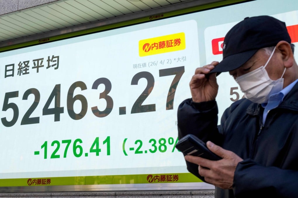 A man stands in front of an electronic board displaying the closing numbers of the Nikkei Stock Average on the Tokyo Stock Exchange, in Tokyo, on April 2. Photo: AFP