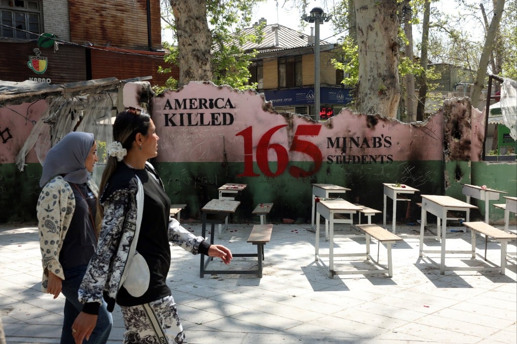 Iranian women walk past a memorial in Tehran to a school that was targeted by a US air strike in February killing 165 children and staff. Photo: EPA