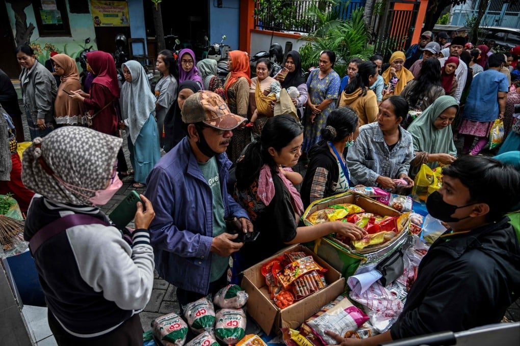 People queue in line to buy necessities at a market in Surabaya. More than 8,000 men have been denied access to public services in the city for failing to pay child support. Photo: AFP
