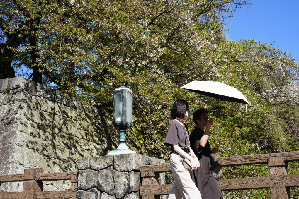 People walk under a parasol in Shizuoka, Japan, where temperatures exceeded 30 degrees Celsius, on April 11. Photo: Kyodo