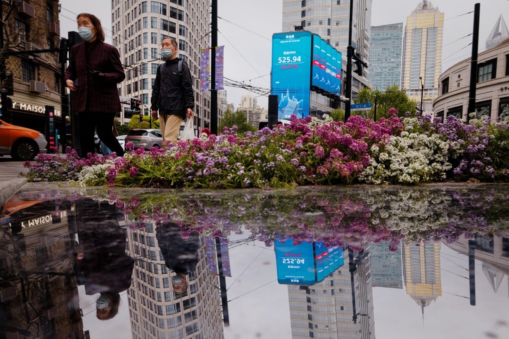 People walk near a screen showing stock exchange and economic data in Shanghai on April 20, 2026. Photo: EPA