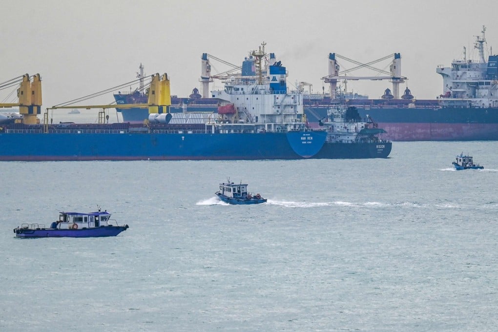 Small boats sail beside vessels anchored in the Strait of Singapore on Tuesday. Photo: AFP