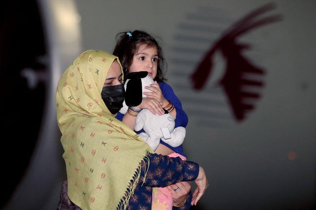 A woman carries a child as they arrive in Qatar with other evacuees from Afghanistan in  2021, following the US withdrawal. Photo: AFP