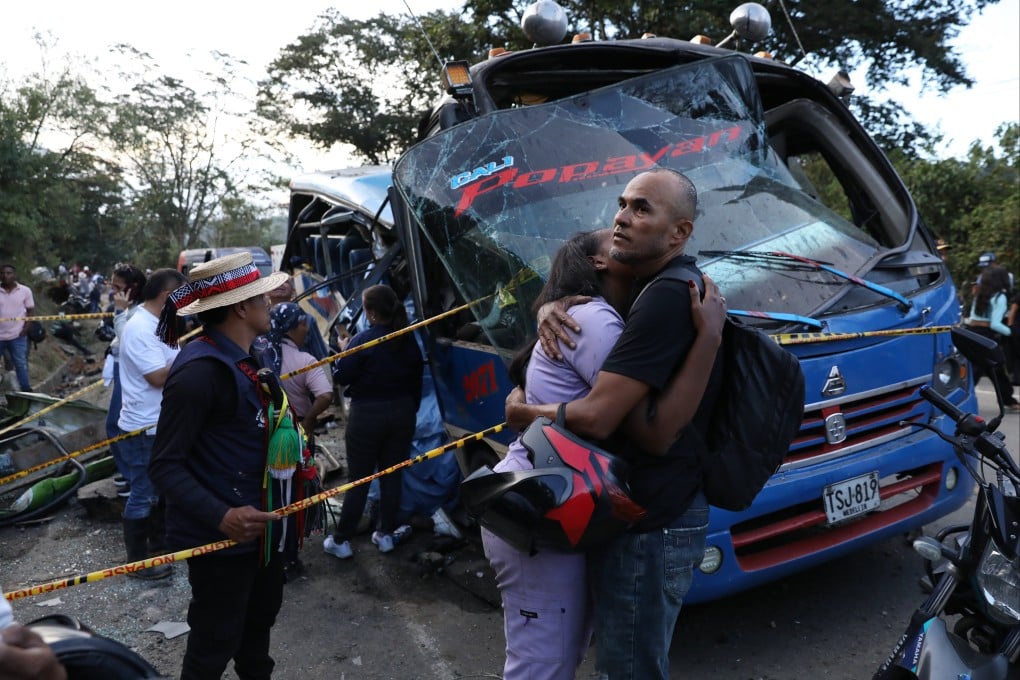 Relatives of victims embrace in front of a bus hit by an explosive device in Cajibio, Colombia, on Saturday. Photo: AP