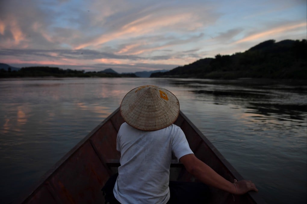 A man sits in a fishing boat on the Mekong River in northeastern Thailand, with Laos seen on the left, in 2019. Photo: AFP