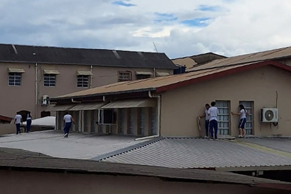 Students at Sao Jose Institute in Rio Branco take cover on the roof while during a shooting incident on Tuesday. Photo: AFP