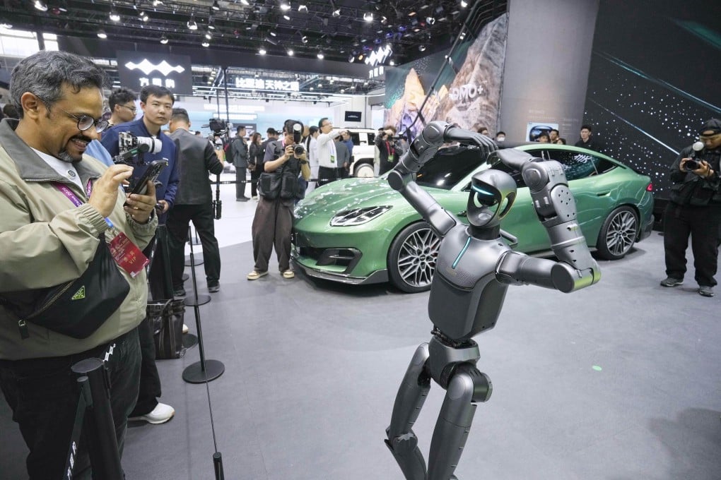 A humanoid robot poses at a BYD booth beside an electric vehicle at the Beijing auto show. Photo: Kyodo