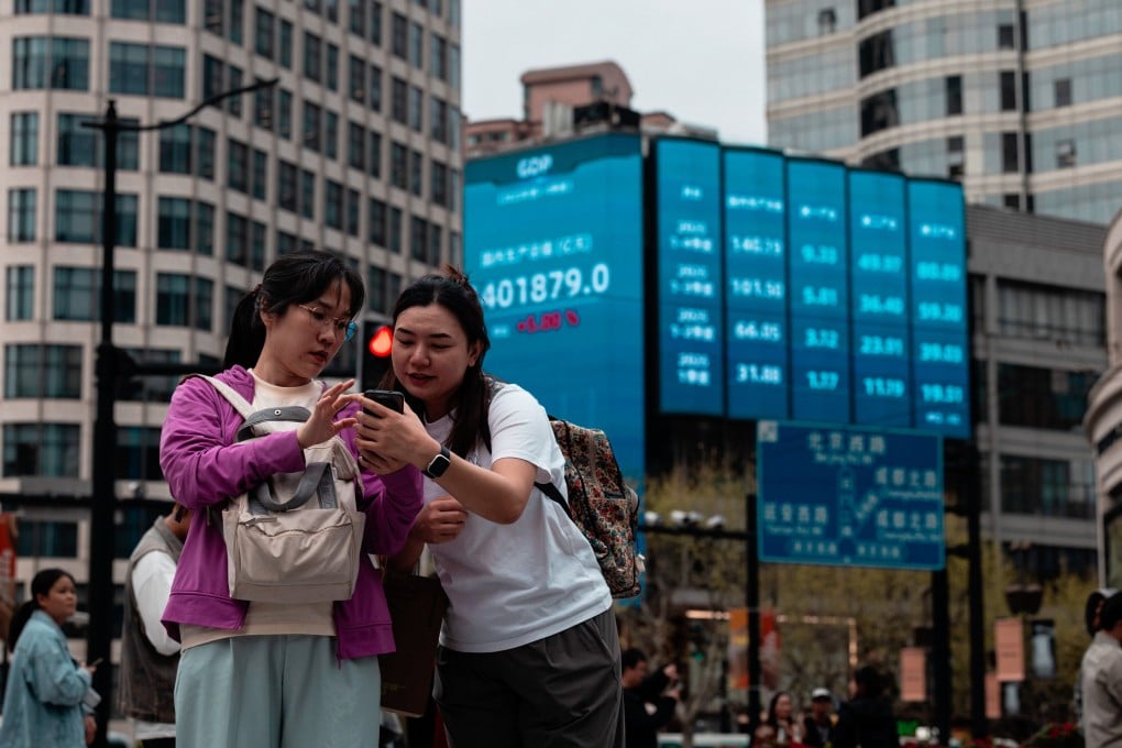 People stand beneath a large screen showing the latest stock prices in Shanghai. Photo: EPA