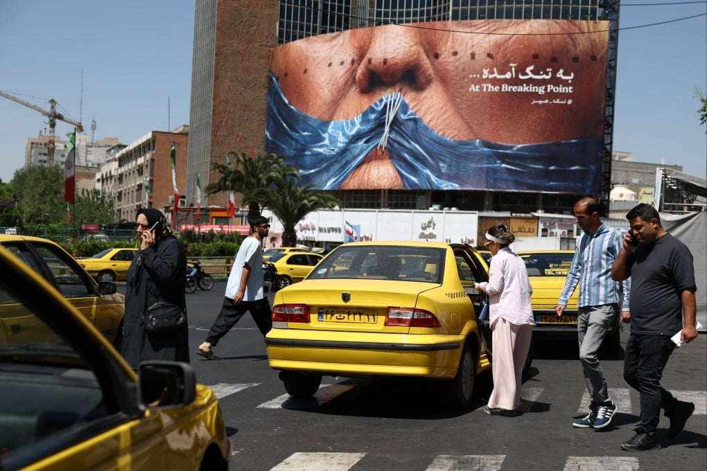 People walk past an anti-US billboard, depicting President Donald Trump and the Strait of Hormuz, in Tehran on May 11. Photo: West Asia News Agency via Reuters
