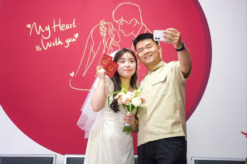 A newlywed couple takes a selfie with their marriage certificates at a marriage registration office in China’s northern Henan province. Photo: Getty Images