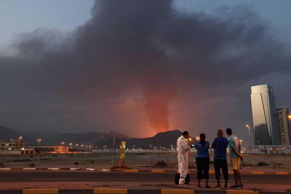 Foreign workers look at a tall plume of black smoke after an explosion in the Fujairah industrial zone in the UAE in March amid the Iran war. Photo: AFP