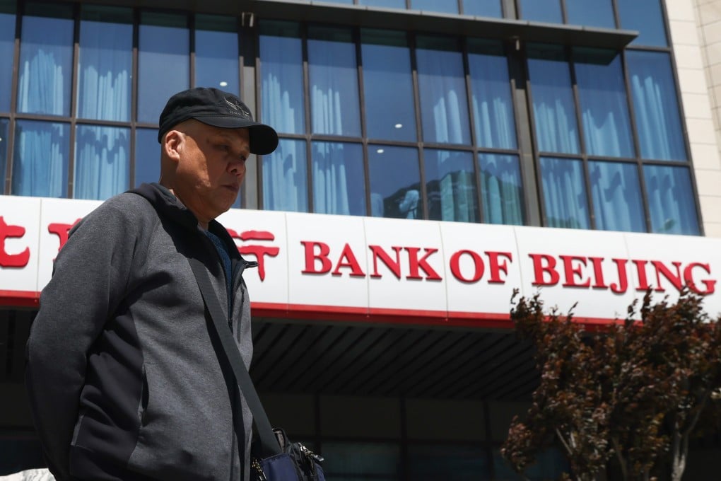 An elderly man walks past a bank branch in the Central Business District in Beijing in April. Photo: EPA-EFE