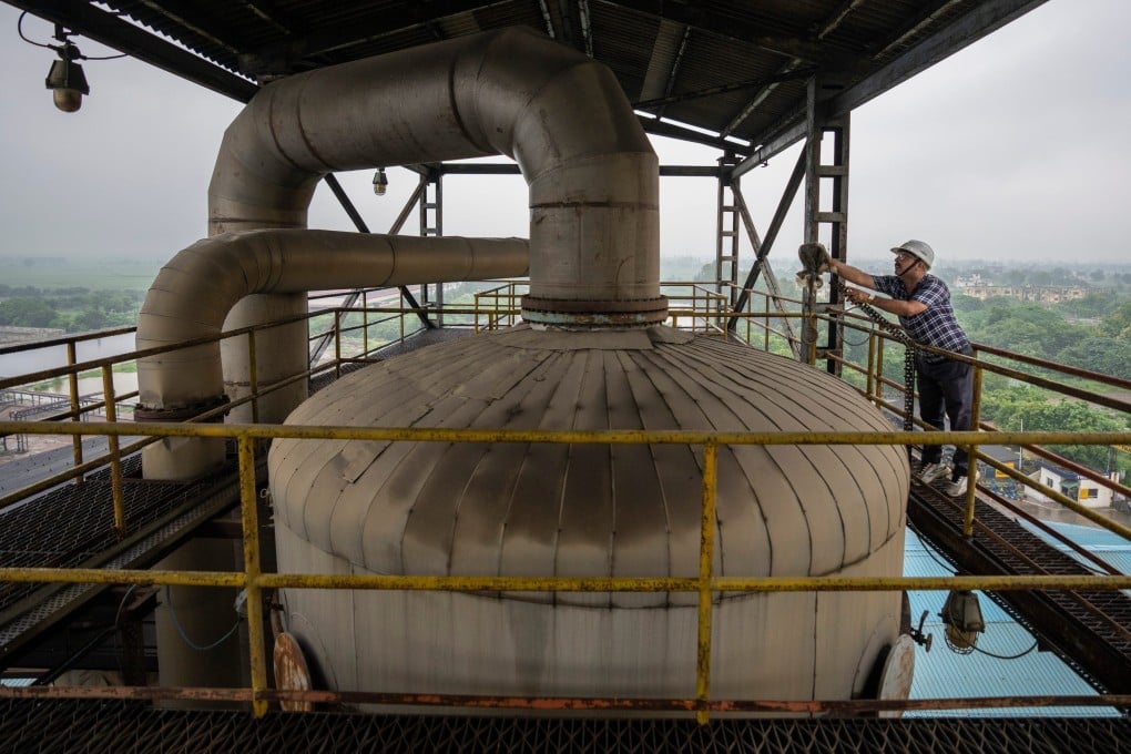 A technician works on the top deck of a distillery at Bajaj Hindustan Sugar factory that produces ethanol in August 2023. Photo: AP