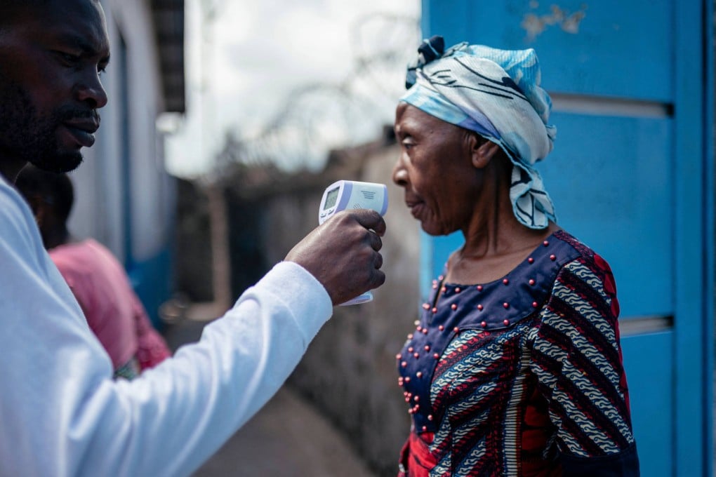 A staff member at the CBCA Virunga Hospital in Goma, in the DRC, checks a visitor's temperature. Photo: AFP