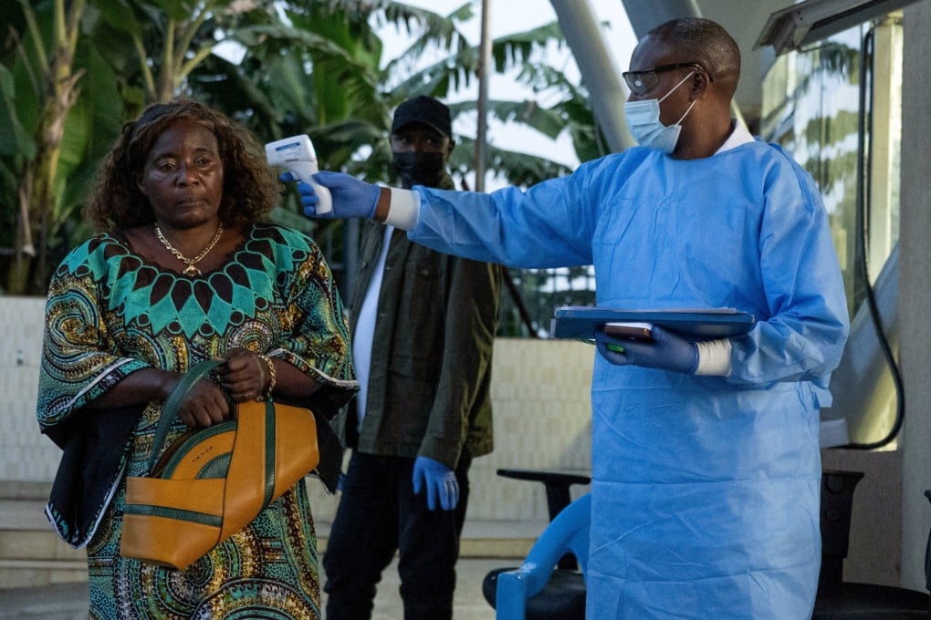 A Congolese health worker checks a woman's temperature at a border crossing point. Photo: Reuters